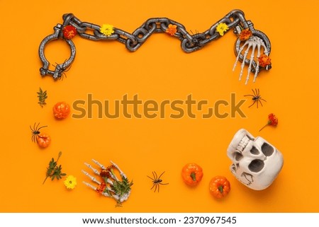 Frame made of skull, shackles, skeleton hands and marigold flowers for Halloween celebration on orange background
