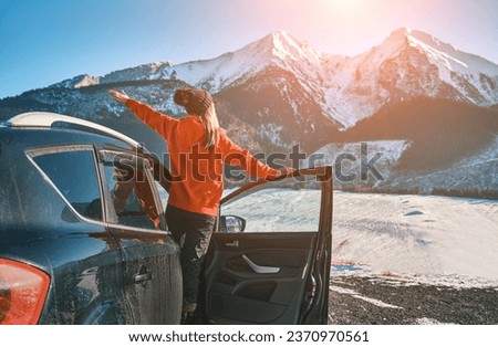 Woman traveling in car, exploring, enjoying the view of the winter mountains landscape.