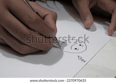 a girl who draws a smile icon on a piece of paper.