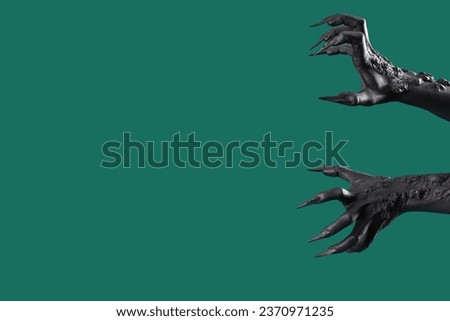 Black hands of witch with claws on green background. Halloween celebration Royalty-Free Stock Photo #2370971235