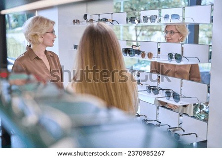 Middle-aged blonde tries on glasses in an opticians salon