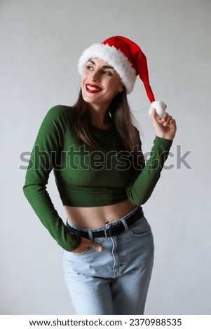 Close up photo of happy excited young brunette woman in santa claus hat isolated over gray background