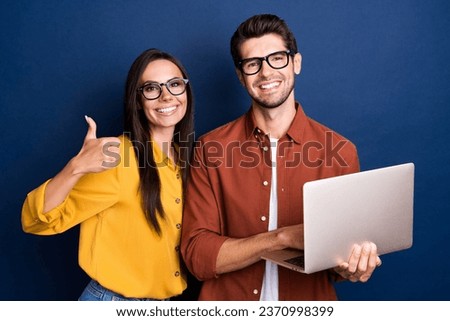 Photo of successful businesspeople hold netbook demonstrate thumb up confirmation isolated on blue color background