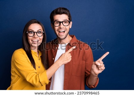 Photo of two impressed cheerful corporate colleagues indicate finger empty space proposition isolated on blue color background