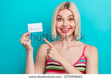 Photo portrait of attractive young woman hold point excited credit card wear trendy striped clothes isolated on cyan color background