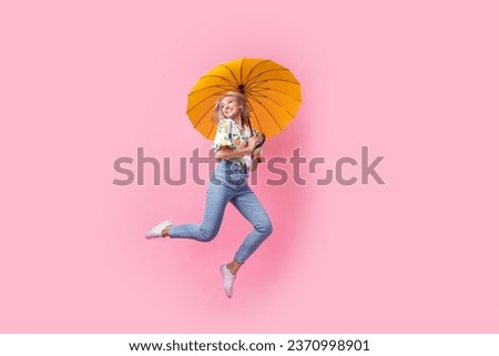 Full body image of careless young woman blonde wavy hair jumping high have fun with umbrella look dreamy isolated on pink color background