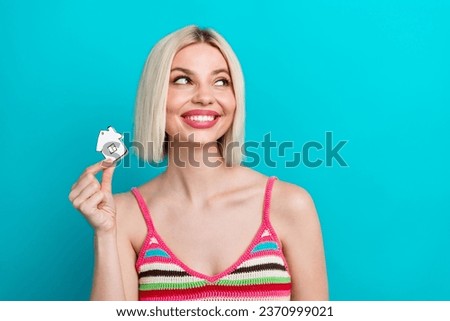 Photo of dreaming young woman striped knitted singlet looking interested novelty with small toy house isolated on cyan color background