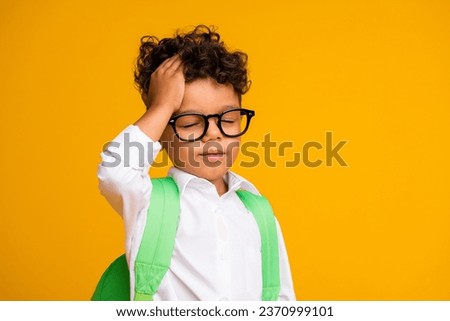Photo of minded pensive little schoolkid closed eyes arm touch head empty space isolated on yellow color background