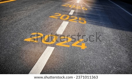 2024 2025 2026 with white dividing lines on black asphalt road surface with sunlight, business chalenge concept and recovery Royalty-Free Stock Photo #2371011363