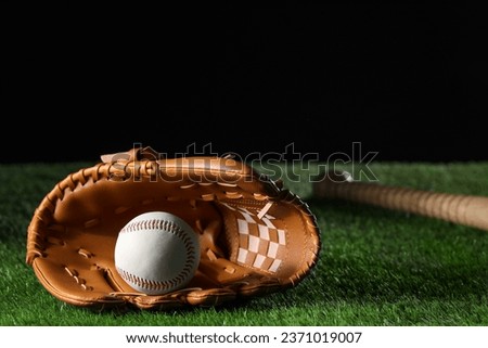 Baseball glove and ball on artificial grass against black background. Space for text
