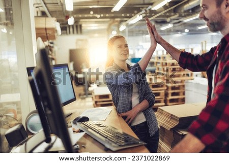 Two diverse colleagues high fiving each other while working in a warehouse Royalty-Free Stock Photo #2371022869
