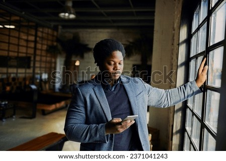 Young African American designer using his smartphone in a startup company office