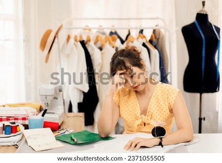 young asian dressmaker feeling stressed and tired from work overtime, woman fashion stylist designer headaches from exhaustion overload, female freelance tailor working at dress shop small business