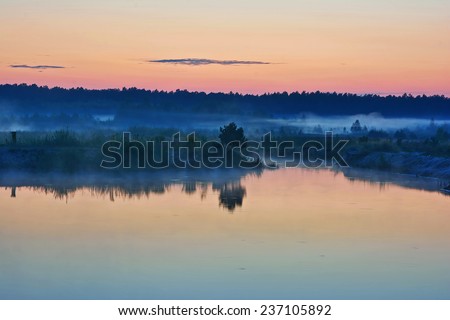 Landscape - Twilight on the lake, the forest in the background and fog on the coast