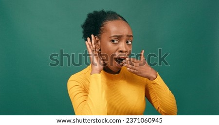 Beautiful Black woman cups ear to listen to gossip, news, surprised, green Royalty-Free Stock Photo #2371060945