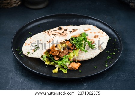 Caucasian flatbread with filling, bread of Armenian cuisine in the form of flatbread stuffed. Snack flatbread with stuffing, chicken, beef, lettuce, arugula, onions and sauce. Royalty-Free Stock Photo #2371062575