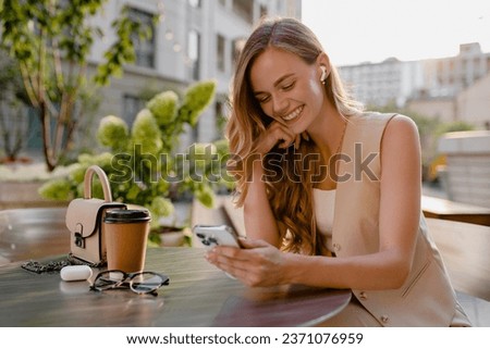 attractive young blond woman sitting in cafe using smart phone drinking coffee in spring summer autumn fashion trend outfit smiling happy wearing beige suit street style, thinking busy and confident Royalty-Free Stock Photo #2371076959