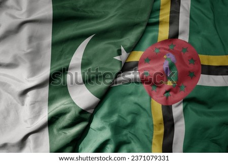 big waving realistic national colorful flag of pakistan and national flag of dominica . macro