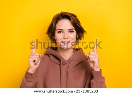 Photo portrait cheerful girl showing new shopping poster up empty space wear brown hood shirt isolated yellow color background