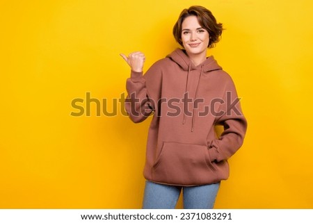 Portrait of amazing promoter lady direct finger side empty space hold hand pocket hoodie shirt isolated yellow color background