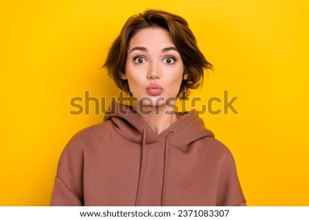Photo portrait of funny pretty lady making duck face sending air kisses flirty mood wear hood shirt isolated yellow color background