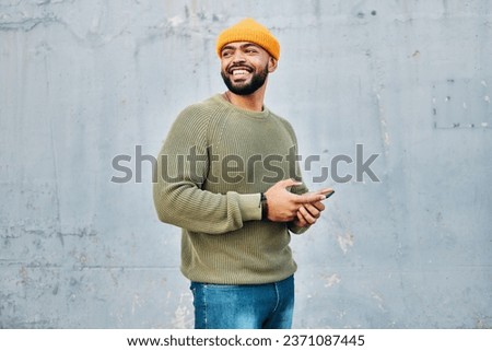 Phone, happy and young man by wall networking on social media, mobile app or the internet. Technology, smile and male person from Colombia scroll on website with cellphone in city by gray background.
