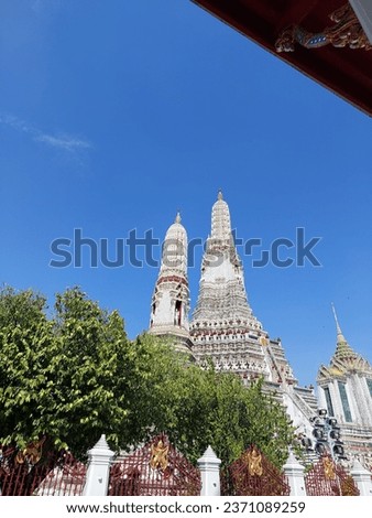 The porcelain Phra Prang Wat Arun (Temple of down) under the bright blue sky and white cloud