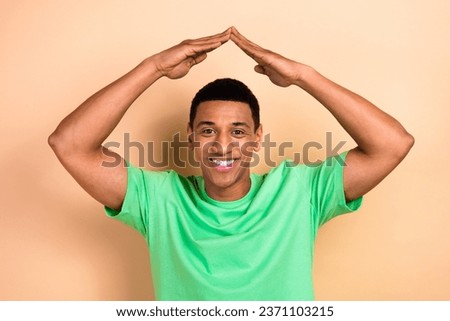 Photo portrait of handsome young male raise hands show roof house sign dressed stylish green outfit isolated on beige color background