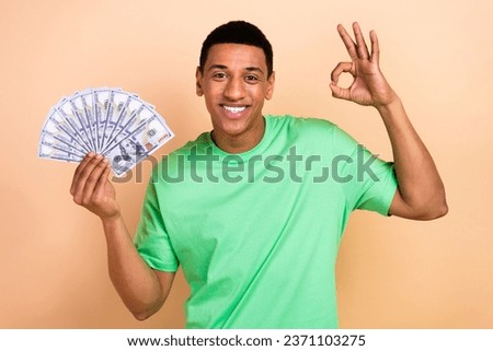 Photo portrait of handsome young guy hold money fan show okey symbol wear trendy green garment isolated on beige color background