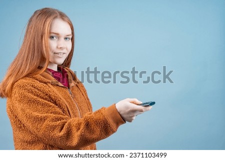 the girl pointed the TV remote to the right on a blue background. TV control