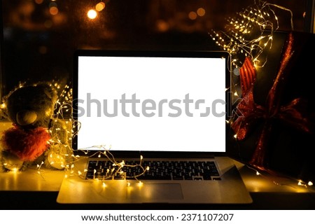Laptop computer with white blank empty mock up screen on Merry Christmas table with presents gifts boxes in warehouse background. Ecommerce website xmas online shopping and shipping delivery, banner