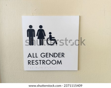 Sign for All Gender Restroom on tan wall.