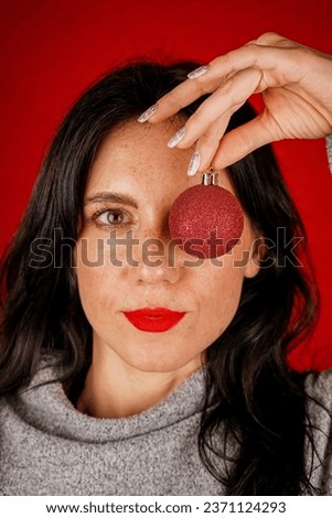 Close-up portrait of an attractive charming cheerful girl. He is holding golden holiday balls for the Christmas tree. New year concept, festive mood