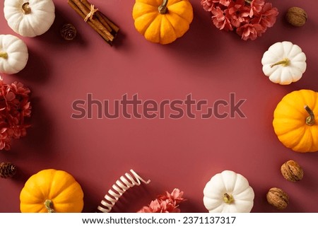 Autumn frame with pumpkins, flowers, fall decor on dark red background.
