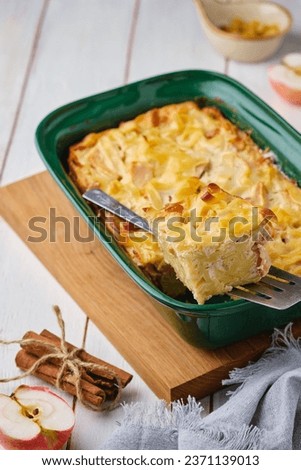 Kugel, a casserole of noodles, cottage cheese, apples and raisins in a green ceramic form on a light wooden background. Jewish cuisine. Noodle dishes. Comfort food.
