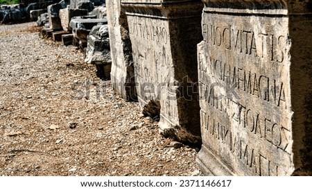 Ruins with Greek inscriptions engraved on them in the ancient city of Perge. Royalty-Free Stock Photo #2371146617