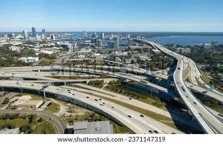 Aerial view of Jacksonville city with high office buildings and american freeway intersection with fast moving cars and trucks. USA transportation infrastructure concept