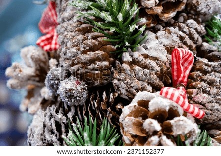 The branch of the Christmas tree is decorated with bows, cones, frozen berries and snow. Close up