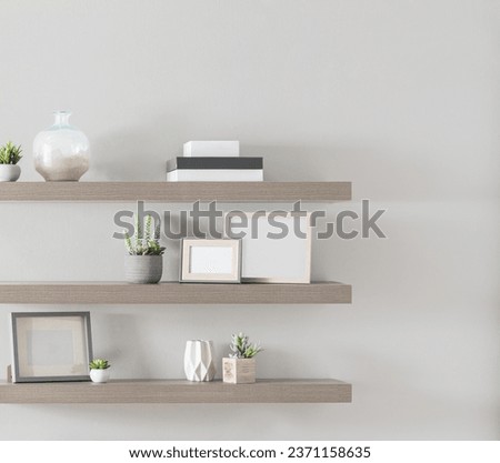 Interior of Living Room Featuring Lightweight Unfinished Floating Gray Wooden Shelf Set with Books, Potted Plants, Picture Frame Mock-ups, and Decorations, Mounted on Light Gray Wall.