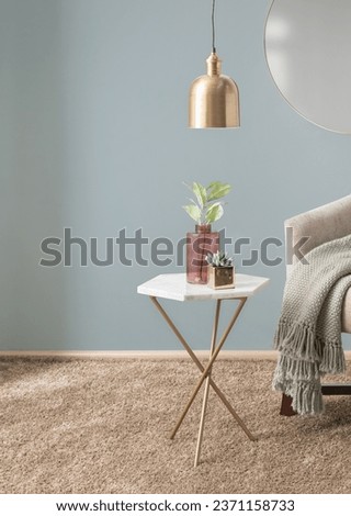 Interior of a Modern Living Room with White Marble Accent Table Featuring a Gold Finish Base Adorned with a Flower Arrangement in Glass Vases and Armchair with a Throw Blanket, Gray Walls. Royalty-Free Stock Photo #2371158733