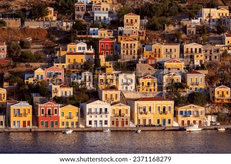 Colorful houses on the slopes of the mountains on Symi island at sunset.