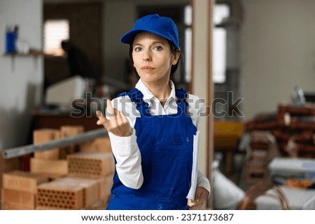 Portrait of builder woman pointing hand at completed room renovation