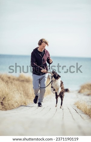Middle aged man playing fetch with his dog on the beach Royalty-Free Stock Photo #2371190119