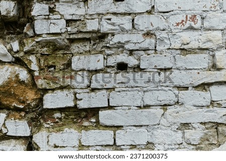 A weathered and aged stone brick wall, showing signs of decay and history, stands as a testament to time and wear