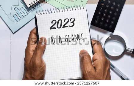 Man holding notepad with the inscription 2023 at a glance. 2023 Year in review, recap, highlights concept.