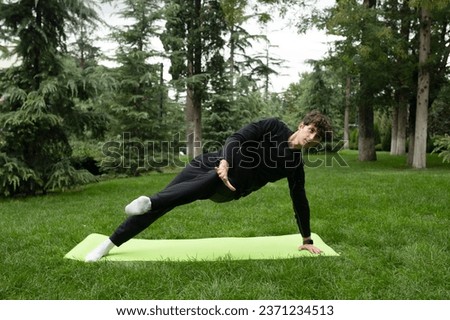 Man doing yoga in the park on the sunny morning. Fit young man exercising outdoors on yoga mat Healthy and active lifestyle concept. Training outdoors.