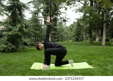 Man doing yoga in the park on the sunny morning. Fit young man exercising outdoors on yoga mat Healthy and active lifestyle concept. Training outdoors.