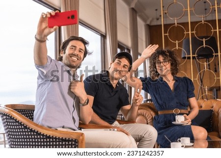 Team work gesturing while taking a selfie sitting on the cafeteria of an hotel