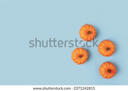 Creative Top view autumn composition. Frame of small pumpkins on a blue paper background. Template fall harvest thanksgiving, anniversary invitation card. Halloween pumpkin flat lay. Horizontal Banner