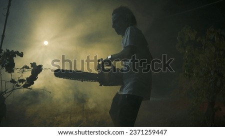Silhouette Of A Crazy Man With Chainsaw In Night Mountain
